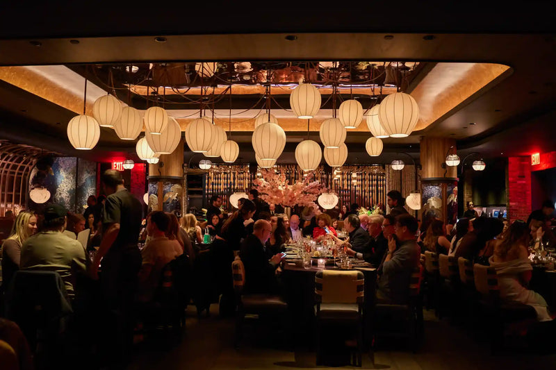 Guests gathered around dining tables beneath warm lights.
