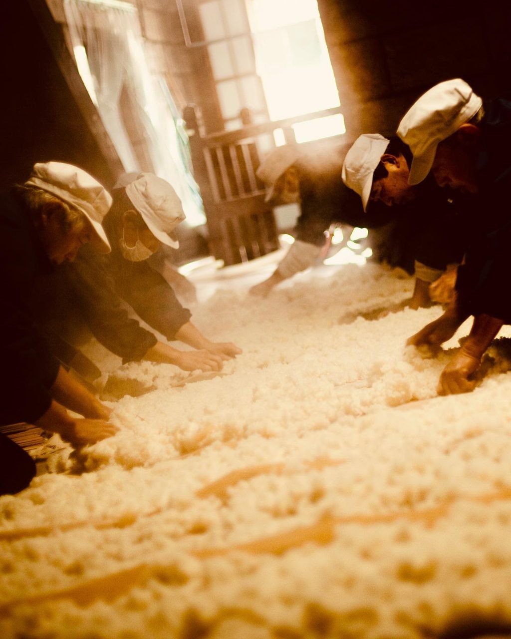 Brewers turning koji rice by hand.